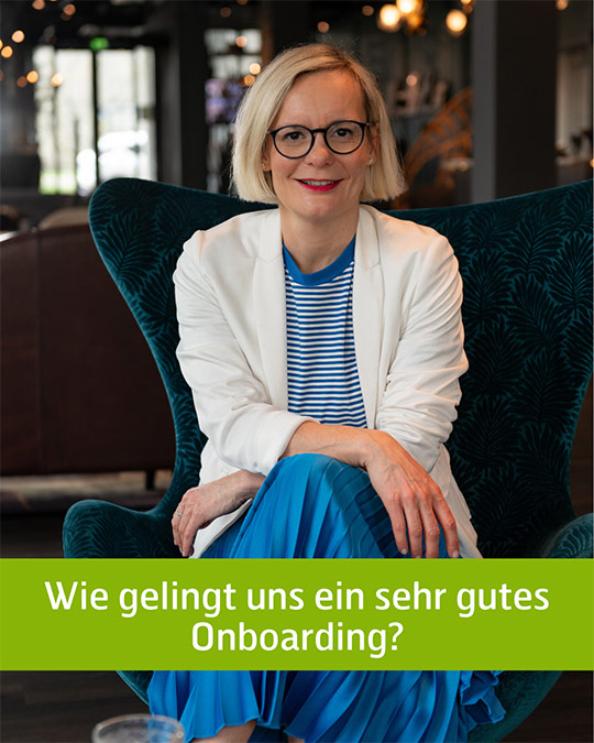 Frau sitzt auf einem Stuhl und lächelt in die Kamera